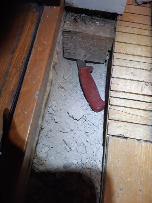 Gamla, skadade parkettgolv vid renovering med synliga golvreglar och murbruk, verktyg synligt.