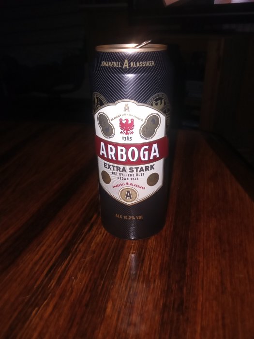 Burk Arboga Extra Stark öl på ett brunt träbord.