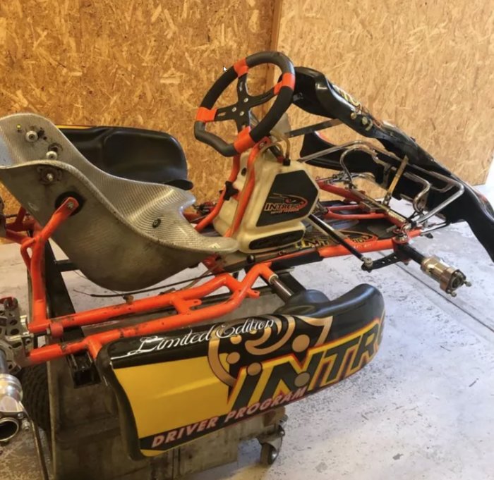 Gokart med orange ram och Racingstol i ett garage som kan omvandlas från en gräsklippare.