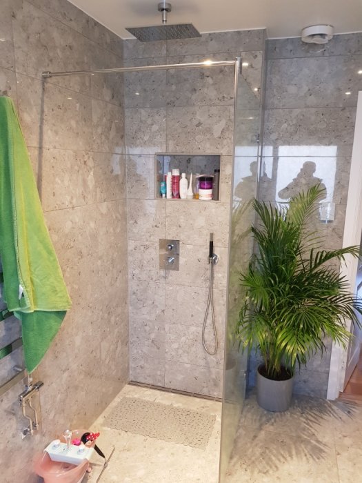 Modernt övervåningsbadrum med duschområde, gröna handdukar och krukväxt.