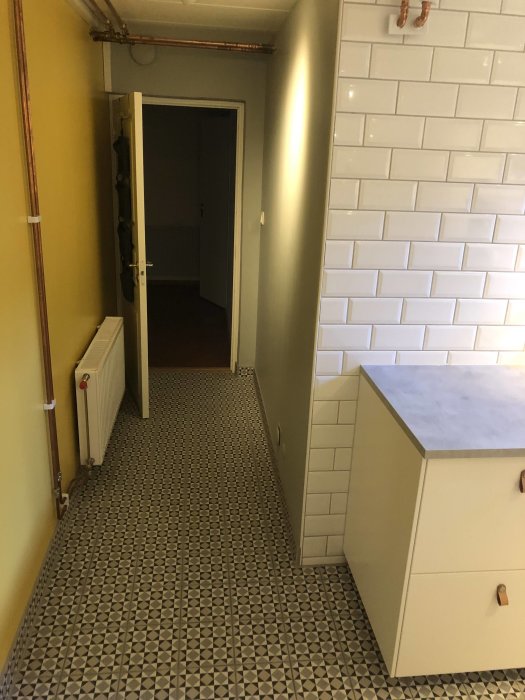 Nyrenoverad tvättstuga med geometriskt mönstrat golv och vita kakelväggar.