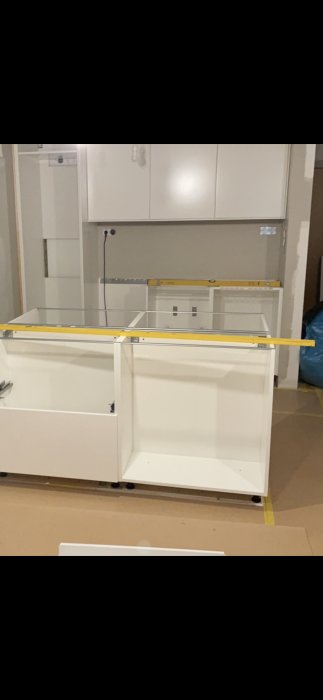 Okaklad vägg ovanför en vit diskbänk med måttstock, i ett kök under renovering.