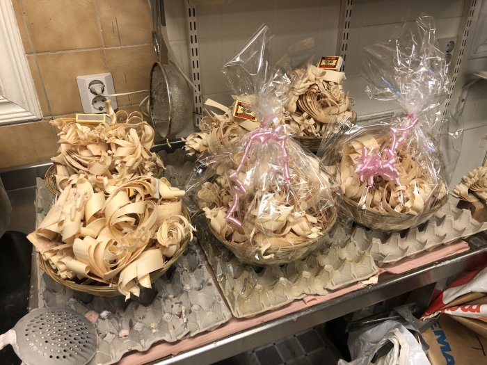 Korgar med handgjorda tändkrusiduller av träspån, inplastade och bundna med rosetter.