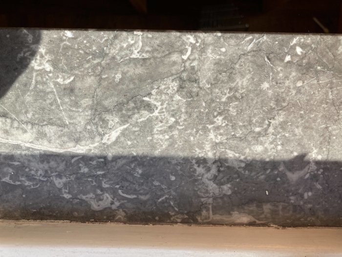 Närbild av en fönsterbräda i grå och vit marmorerad sten från 60-talet.