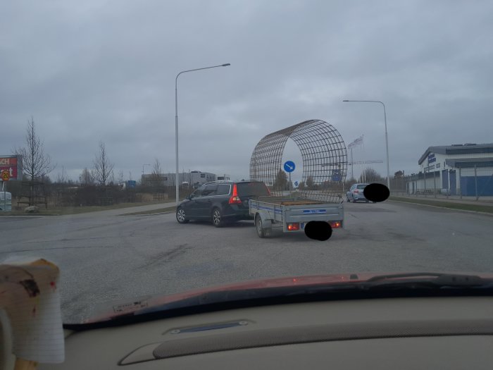 Bil som drar släp med stort metallgitter i form av en båge, säkrat med lastpall på tvärs.