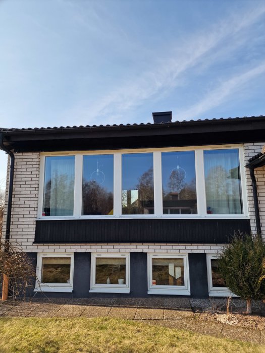 Ett hus med stort fönsterparti och en synlig dropplåt ovanför, utan tegel för montering av markiser.
