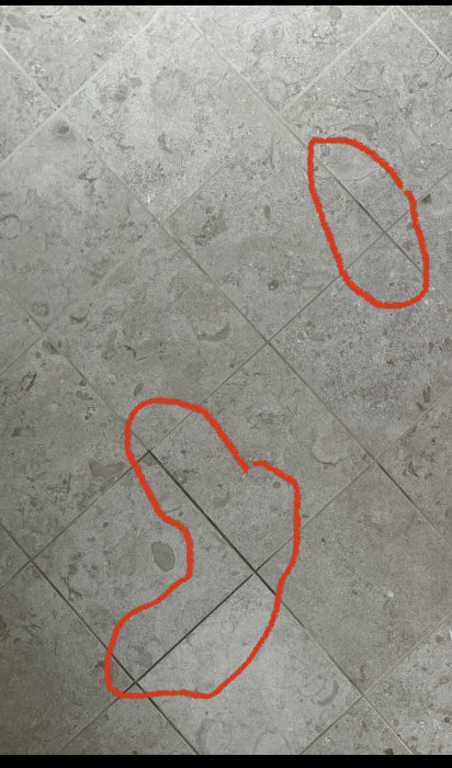 Grå kakelgolv med ojämnt färgade foglinjer markerade med orange.