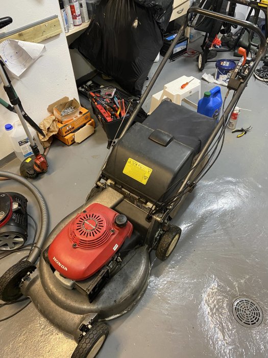 Honda HRD536C gräsklippare med rött motorhuv inkörd i ett verkstadsutrymme.