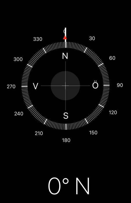 Kompass med röd visare pekande nära 0 grader nord på en svart bakgrund.