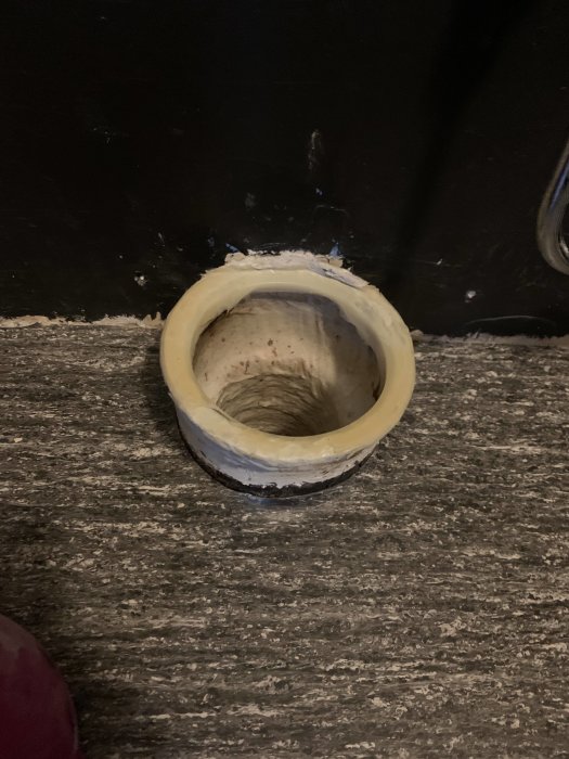 Utskjutande avloppsrör i golv med synliga "läppar" som problematiserar installation av toalettstol.