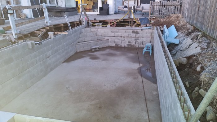 Nybyggnation av källarutrymme med betongväggar och -golv, arbetsmaterial synligt.