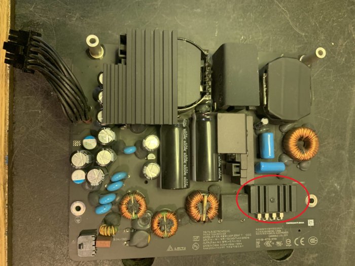 Elektronikprint med kondensatorer, induktorer och en synlig skada markerad med en röd cirkel.