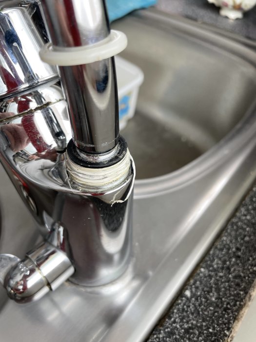 Köksblandarens pip med synlig kalk och slitage, fast vid vasken utan synligt spärrstift.