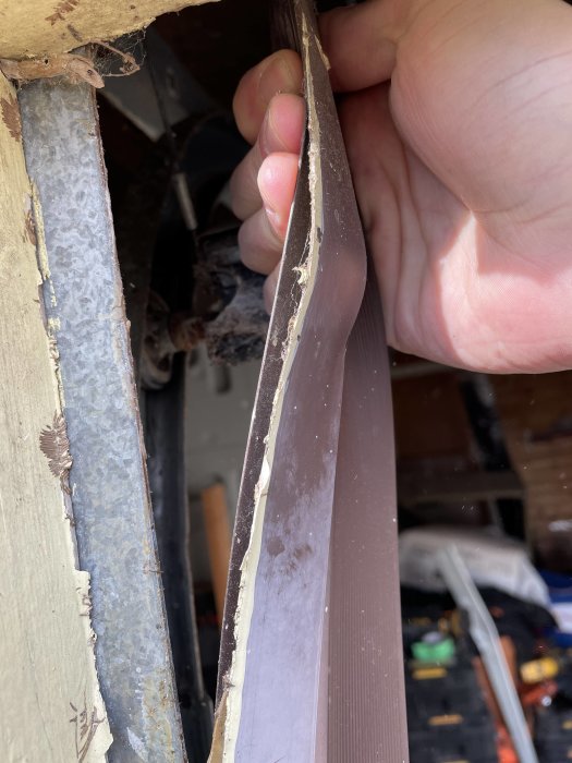 Närbild på ett skadat brunt plastskydd vid en garageport med markerade kanter.