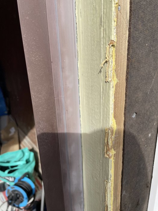 Slitet plastskydd vid kanten av en garageport, skadat och flagande, markerat i rött.
