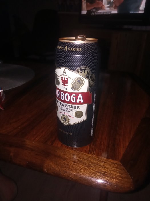En burk Arboga Extra Stark öl på ett träbord framför en TV-skärm.