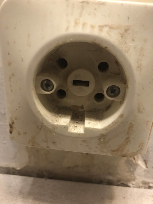 Närbild på ett använt perilexuttag för spis, med synliga smutsavlagringar.