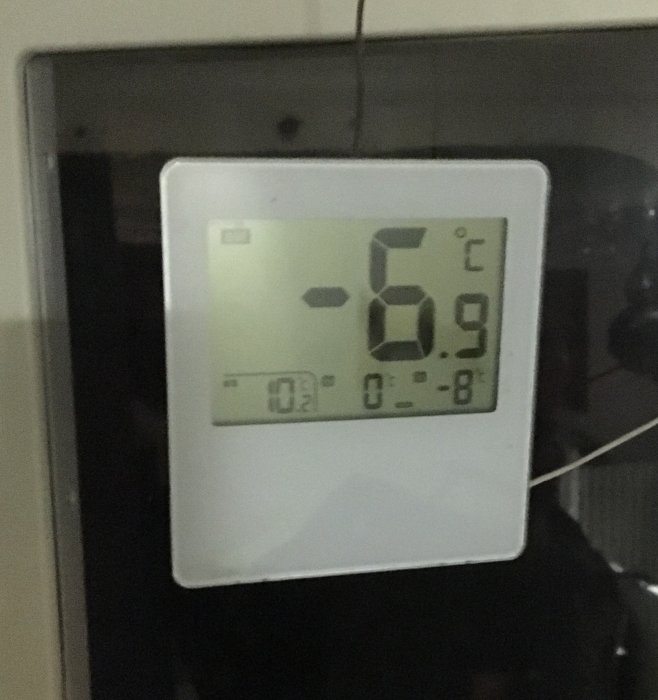 Termometer visar -6,9 °C med reflektion av en persons silhuett i bakgrunden.