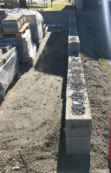 Nybyggd stödmur vid uppfart med grus och singel inför påfyllning och packning.