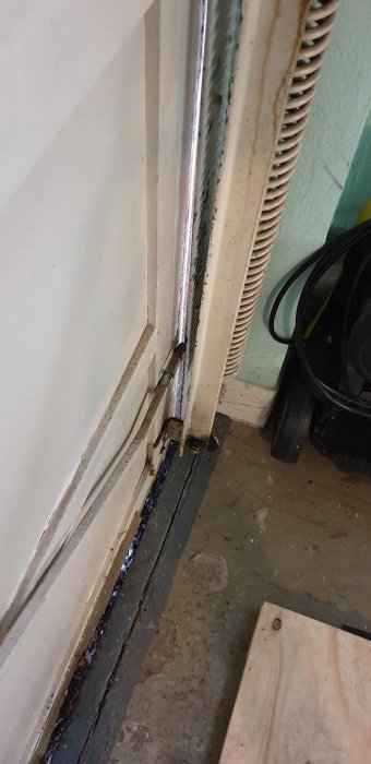 Gamla garagevipport som inte stänger ordentligt mot golvet, synliga gångjärn och slitage.