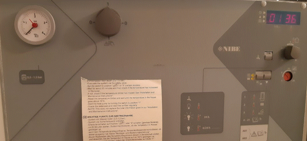 Värmepannans kontrollpanel med termometer visande nästan 0 och display med temperatur 36 grader Celsius.