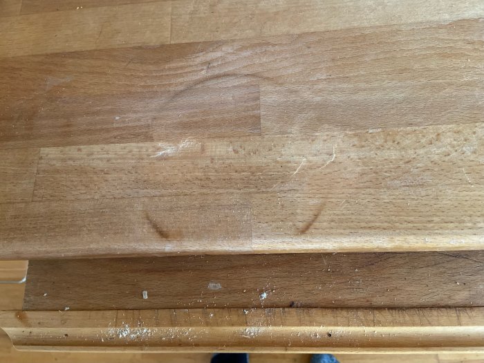 Trädiskbänk med brännmärke och repor, i behov av renovering.