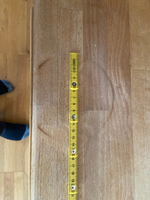 Brännmärke på trädiskbänk med mätande tumstock ovanpå.