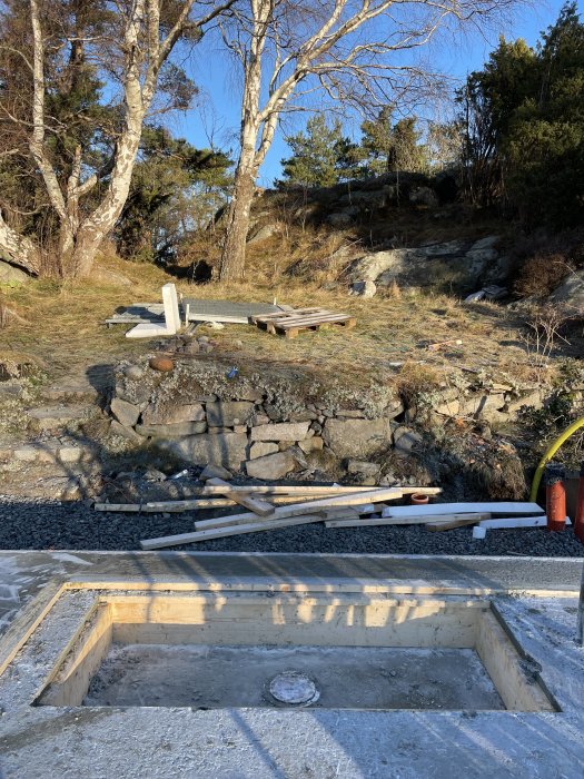 Betongform för badkar under konstruktion med utsikt över träd och klippig natur.