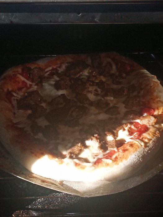 Hemlagad kebabpizza gräddas i ugnen med synligt ost och kebabkött.