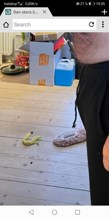 Skalad banan på ett trägolv med dunkar och en person delvis i bild.