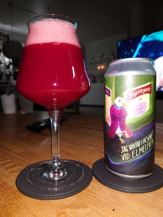 Rosefärgad öl i ett glas bredvid en ölburk från Stigbergets på ett bord.