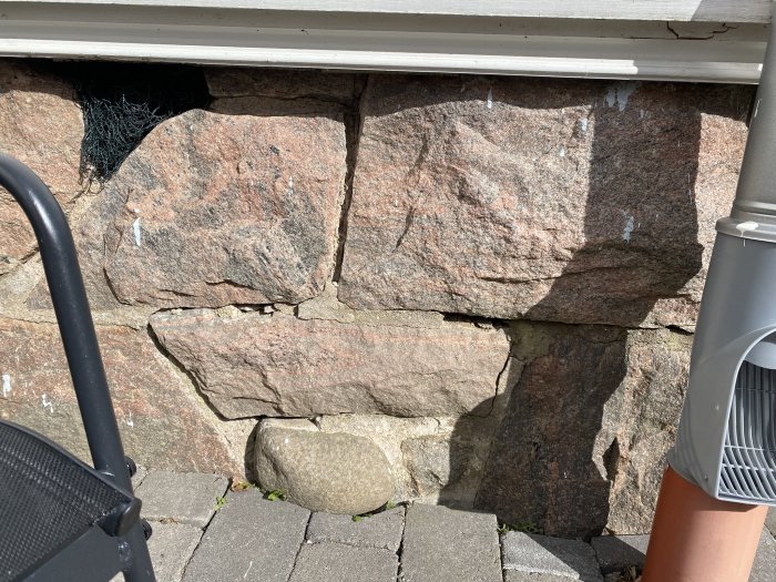 Skadade fogar mellan granitblock i grundmur med synliga lagningar.