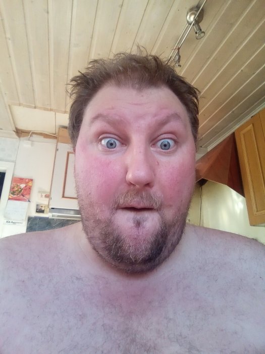 Man med överraskat uttryck i en inomhusmiljö, tagen på nära håll.