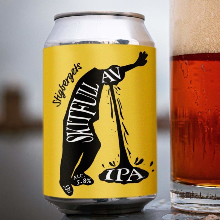 Burk med Sigtunabrygghus Skitful IPA öl bredvid ett glas med öl på en bordsskiva.