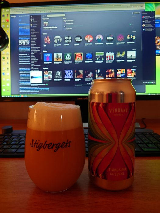 Ölglas märkt "Stigbergets" och burk från "Verdant", framför datorskärm med musikspelarprogram.