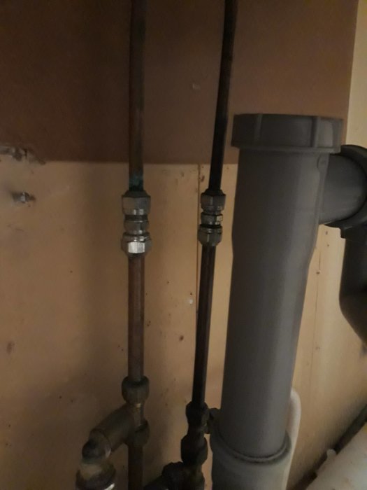 Vattenrör i koppar anslutna till avstängningsventiler under en diskbänk som ska pluggas.