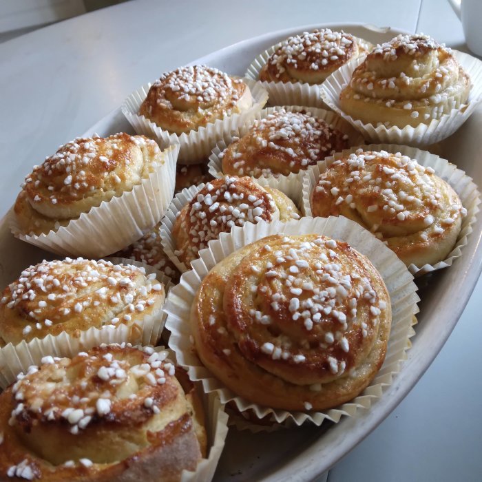 Hembakade vaniljbullar på ett fat med pärlsocker på toppen.