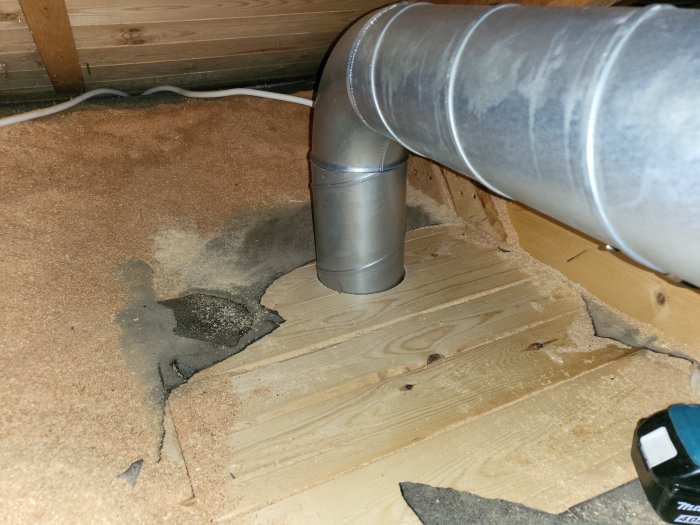 Isoleringsmaterial runt ett ventilationsrör som ansluter till en fläktkonvektor under ett träloft.