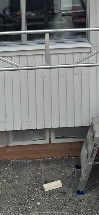 Källarfönster delvis dolda av nysatt fasad som slutar några centimeter ovanför fönsteröppningar.