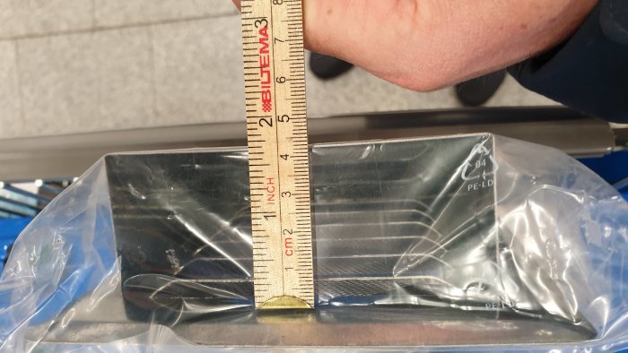 Mätning av en lågprofilerad takhuv med tumstock för installation under solpaneler.