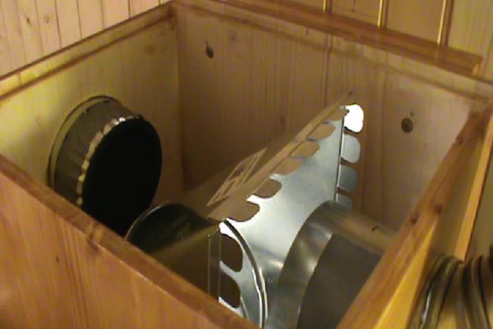 Öppen lucka som visar installation av rör kopplat till en tömningsfläkt i ett trähus.