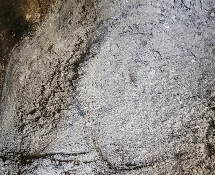 Närbild på aska och kolbitar i en Keddy-kamin efter en brasa.