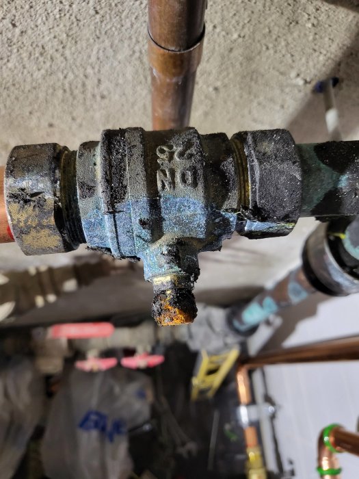 Avstängningsventil med rörkoppling och synlig gänga, saknar klämring och mutter, bakgrund av otydligt VVS-arbete.