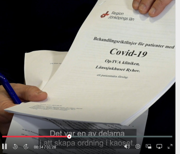 Hand håller i en behandlingsmanual med titeln "Behandlingsriktlinjer för patienter med Covid-19" från Region Jönköpings län.