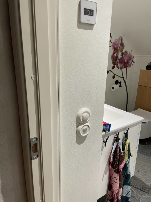 Rörelsesensor installerad bredvid en dörr för att styra automatisk badrumsbelysning.