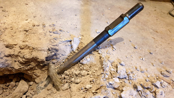 Spett fastkilat i betong vid bilningsarbete nära ett ingjutet vattenrör i källargolv.