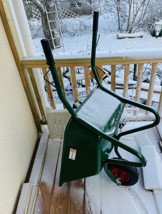 Grön Hörby bruk skottkärra modell B35K med snö på vinterns veranda.