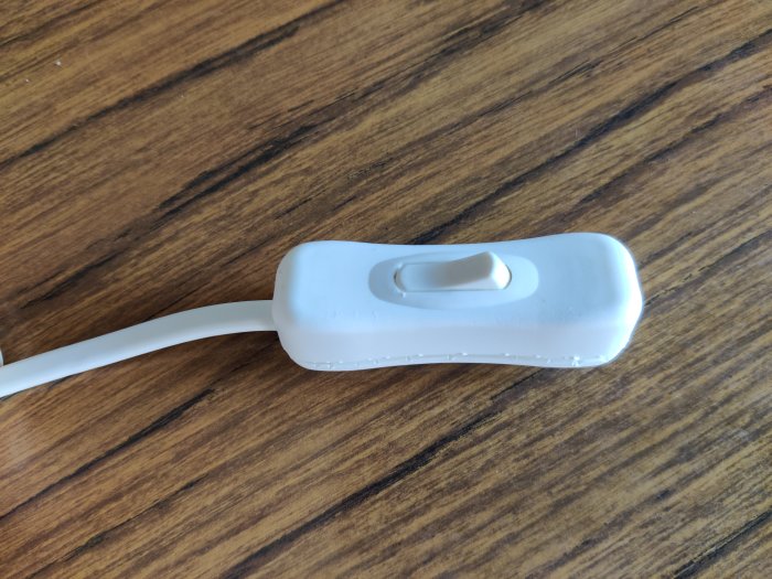 Närbild på en vit kabel med en isärmonterad kabelanslutning och klippt ände.
