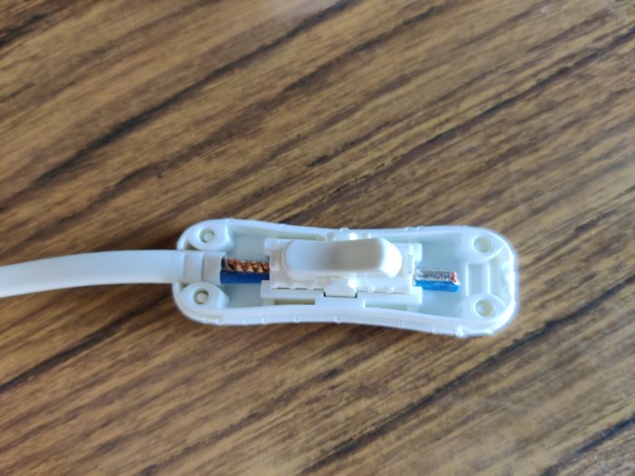 En öppen kabelskarv där ena sidans kabel är avklippt och de oskyddade trådarna syns.