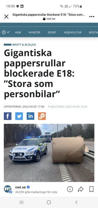 Polisbil och brandbil vid vägrenen nära en stor pappersrulle på vägbanan.